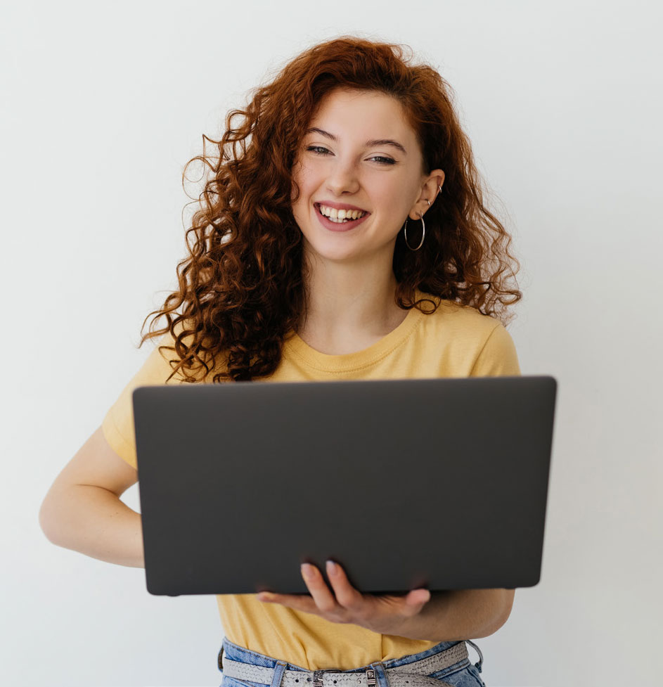 Person standing and smiling with a laptop